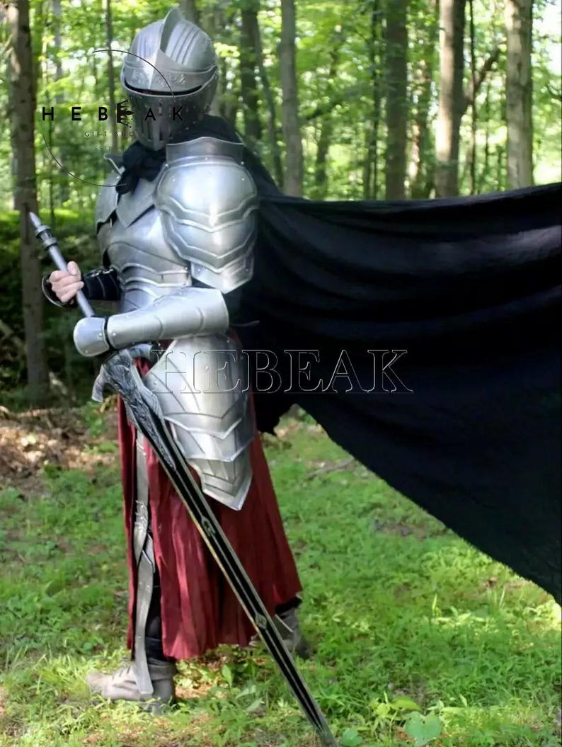 May include: A full body suit of silver armor with a black cape and a sword. The armor has a helmet with a visor and a skirt. The person is standing in a forest.