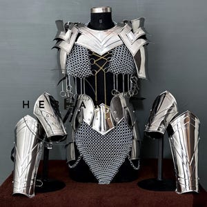 Puede incluir: Un conjunto completo de armadura plateada pulida, que incluye peto, hombreras y protectores de brazos. La armadura presenta detalles intrincados y detalles de cota de malla, exhibida en un maniquí negro. Para recreaciones históricas o disfraces.