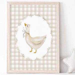 May include: A framed print with a white goose with a brown bow on a white background with a brown and white gingham border.