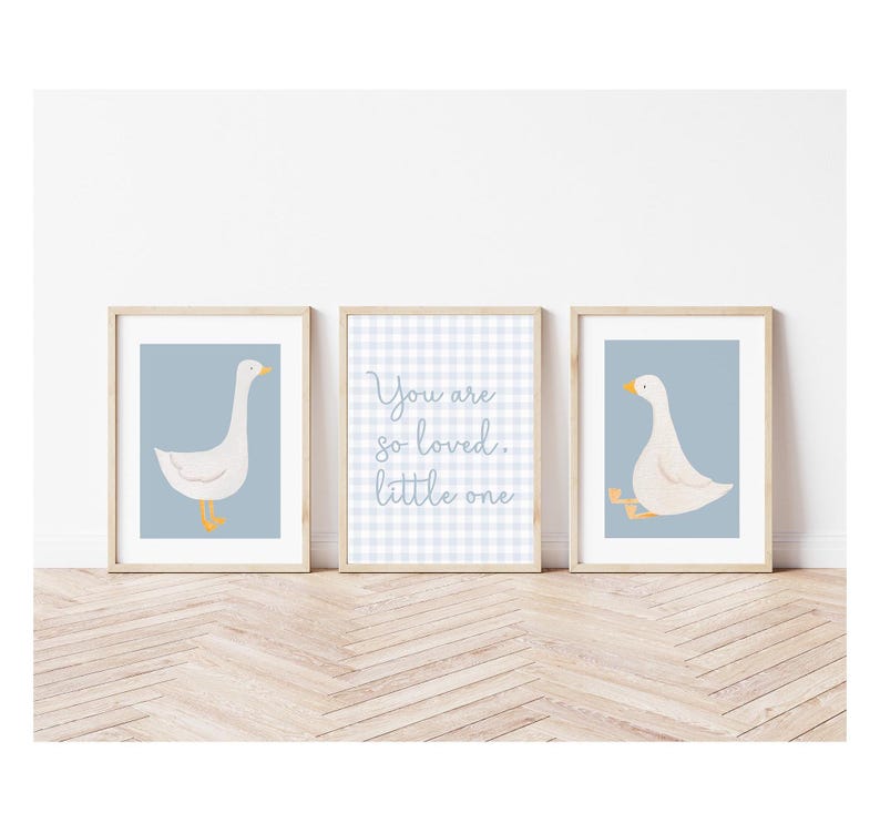 May include: Three framed prints with a blue background. The center print has a white and blue gingham pattern with the text "You are so loved. little one". The prints on either side feature a white goose with orange feet on a blue background.