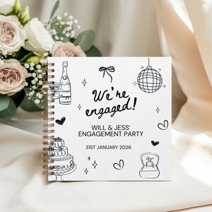 Może przedstawiać: Spiralny notatnik z białą okładką z czarnymi ilustracjami i napisem "We're engaged!". Data "31 stycznia 2026" jest r&oacute;wnież uwzględniona, wraz z nazwiskami "WILL & JESS' ENGAGEMENT PARTY".