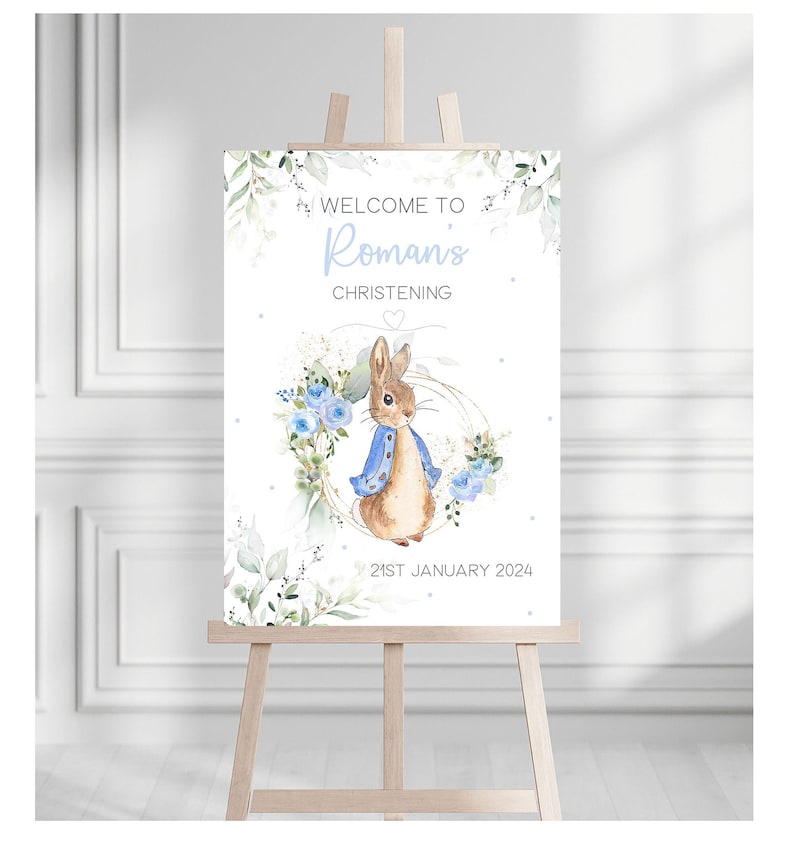 Op de afbeelding: Welkom op het doopbord van Roman met een aquarel-illustratie van Peter Rabbit in een blauw jasje, omringd door blauwe bloemen en groen. De datum is 21 januari 2024.