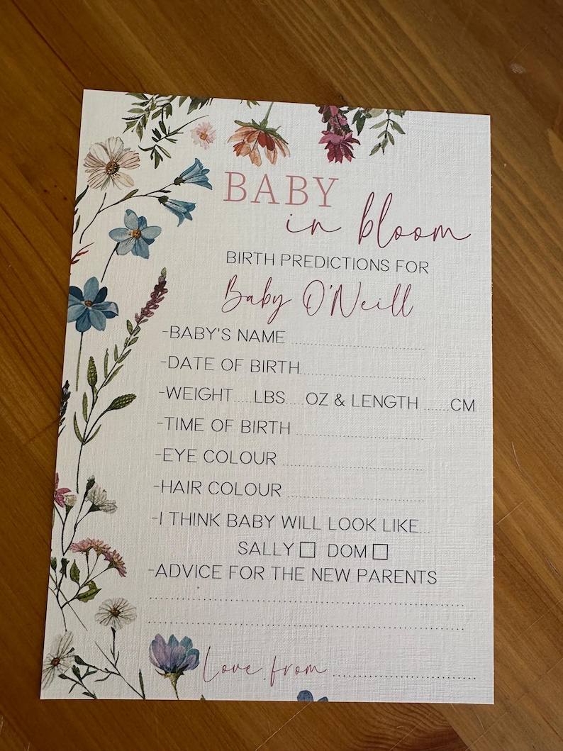 May include: A baby shower game card with the text "BABY in bloom" and "Birth Predictions for Baby O'Neill". The card is decorated with floral illustrations in shades of blue, pink, and white. It includes prompts for baby's name, date of birth, weight, and more.
