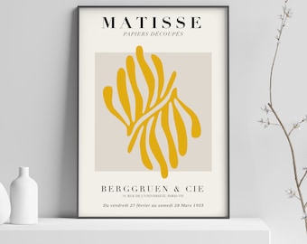 以下が含まれることがあります： 上部に「MATISSE PAPIERS DÉCOUPÉS」というテキストが書かれた白黒のポスター。ポスターは、薄いベージュの背景に黄色の抽象的なデザインが描かれている。ポスターの下部には、「BERGGRUEN & CIE 70, RUE DE L'UNIVERSITÉ, PARIS-VII Du vendredi 27 février au samedi 28 Mars 1953」というテキストが書かれている。