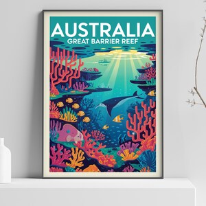 Op de afbeelding: Ingelijste kunstafdruk met een levendige illustratie van het Great Barrier Reef in Australi&euml;. Het kunstwerk toont kleurrijk koraal, vissen en een walvis, met het woord "AUSTRALIA" bovenaan. De kleuren zijn blauw en groen.