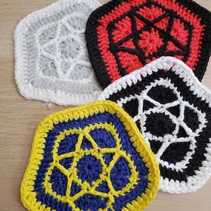 May include: Four crocheted hexagons with a starburst design in the center. The hexagons are in the colors gray, red, black, and yellow with blue.