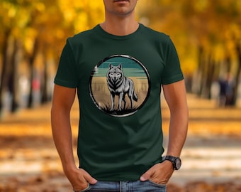 May include: Dark green t-shirt featuring a circular graphic of a wolf standing in a field. The wolf is gray and white, set against a backdrop of a sunset and trees. The shirt is short-sleeved and worn by a person.