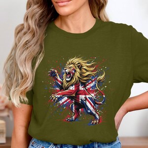 Op de afbeelding: Een olijfgroen t-shirt met korte mouwen en een grafische print van een brullende leeuw die op zijn achterpoten staat. De leeuw is gekleurd met het rood, wit en blauwe patroon van de Britse vlag, omringd door kleurrijke verfspatten.