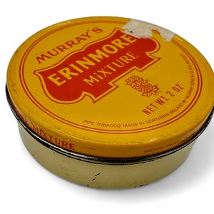 May include: A yellow tin with red lettering that reads "Murray's Erinmore Mixture" and "Pipe Tobacco Made in Northern Ireland by Murray Sons & Co Ltd Belfast". The tin is labeled "Net Wt. 2 oz" and "Vacuum Packed".