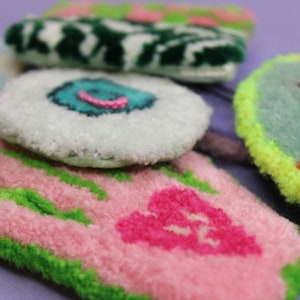 Può includere: Un set di cinque ornamenti fatti a mano, morbidi e colorati. Gli ornamenti hanno la forma di cerchi e presentano diversi motivi e colori, tra cui verde, bianco, rosa e blu.