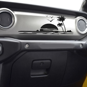May include: Black vinyl decal featuring a sunset scene with palm trees and birds. The decal is designed to be applied to a vehicle's dashboard, adding a decorative touch. The design is a silhouette.