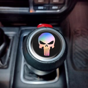 May include: A black gear shift knob with a silver trim and a holographic skull emblem. The skull design features a rainbow gradient effect on a black background, adding a unique touch to the car's interior.