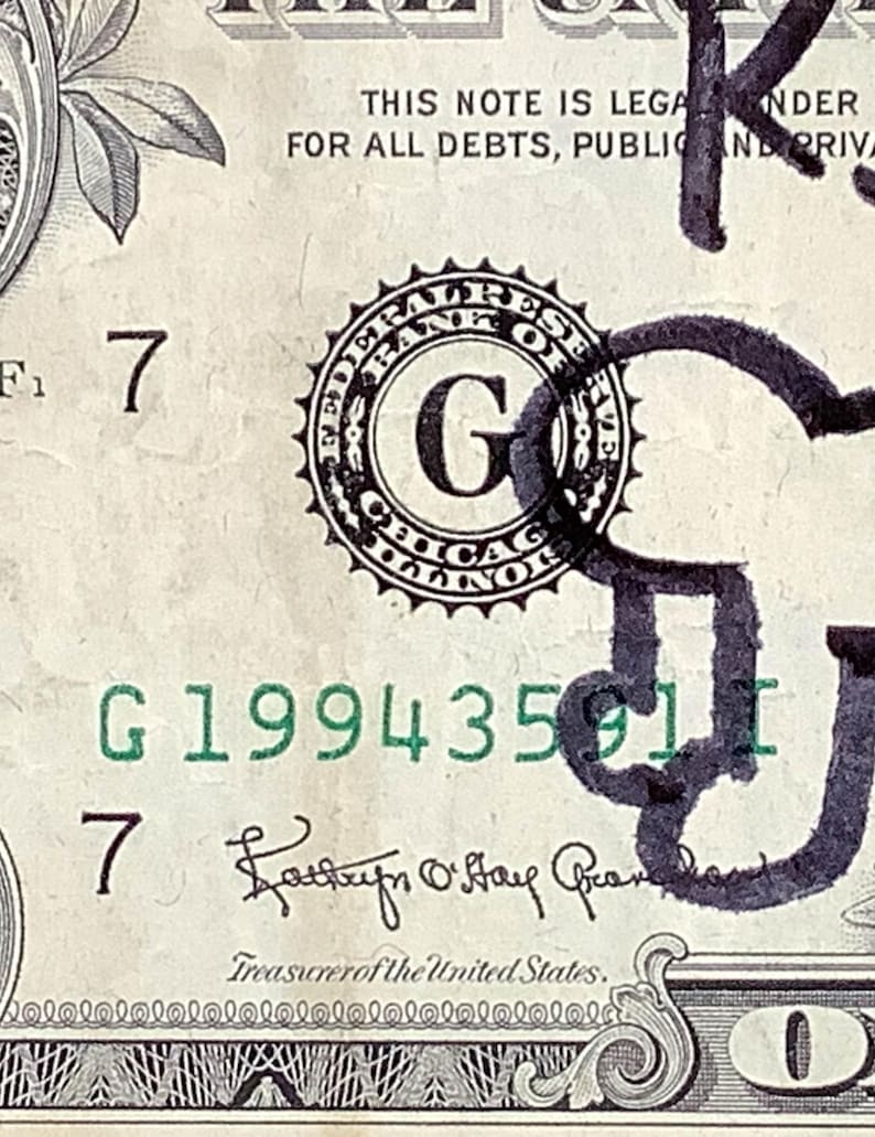 K&ouml;nnte beinhalten: Nahaufnahme einer Ein-Dollar-Note mit dem Text "THIS NOTE IS LEGAL TENDER" und der Seriennummer G19943591I. Die Note zeigt ein Federal Reserve Siegel und die Unterschrift des Schatzmeisters der Vereinigten Staaten.