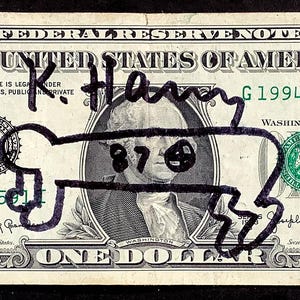 K&ouml;nnte beinhalten: Ein Ein-Dollar-Schein mit einer schwarzen Markierung, die eine Knochenform &uuml;ber dem Portr&auml;t von George Washington darstellt. Auf der Rechnung steht mit schwarzem Marker "K. Hany". Die Seriennummer der Rechnung lautet G19943591I.