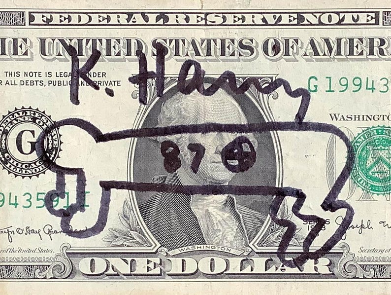 K&ouml;nnte beinhalten: Ein Ein-Dollar-Schein mit schwarzen Markierungen &uuml;ber dem Portr&auml;t von George Washington. Die Zeichnungen enthalten den Namen "K. Harry" und ein cartoonartiges Gesicht &uuml;ber Washingtons Gesicht. Der Text der Rechnung ist sichtbar.