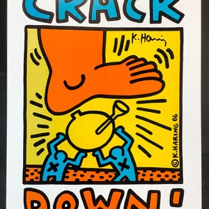 Puede incluir: Una colorida impresión de arte pop con las palabras "CRACK DOWN!" en azul y naranja. La obra de arte presenta un gran pie naranja a punto de pisar un objeto amarillo sostenido por dos figuras azules.