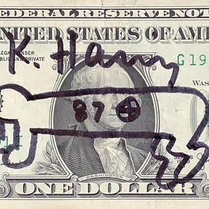 K&ouml;nnte beinhalten: Ein Ein-Dollar-Schein mit einer schwarzen Markierung, die eine cartoonartige Figur &uuml;ber dem Portr&auml;t von George Washington zeigt. Der Schein tr&auml;gt den Text "FEDERAL RESERVE NOTE" und "THE UNITED STATES OF AMERICA". Der Schein ist mit "K. Henry" signiert.