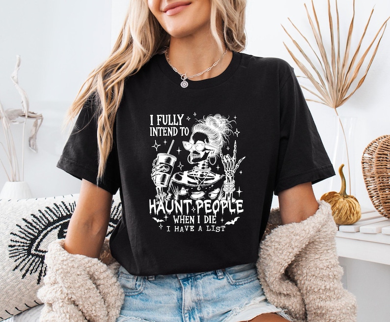 May include: Black t-shirt with a white graphic of a skeleton wearing sunglasses and holding a drink. The text reads "I fully intend to haunt people when I die, I have a list."