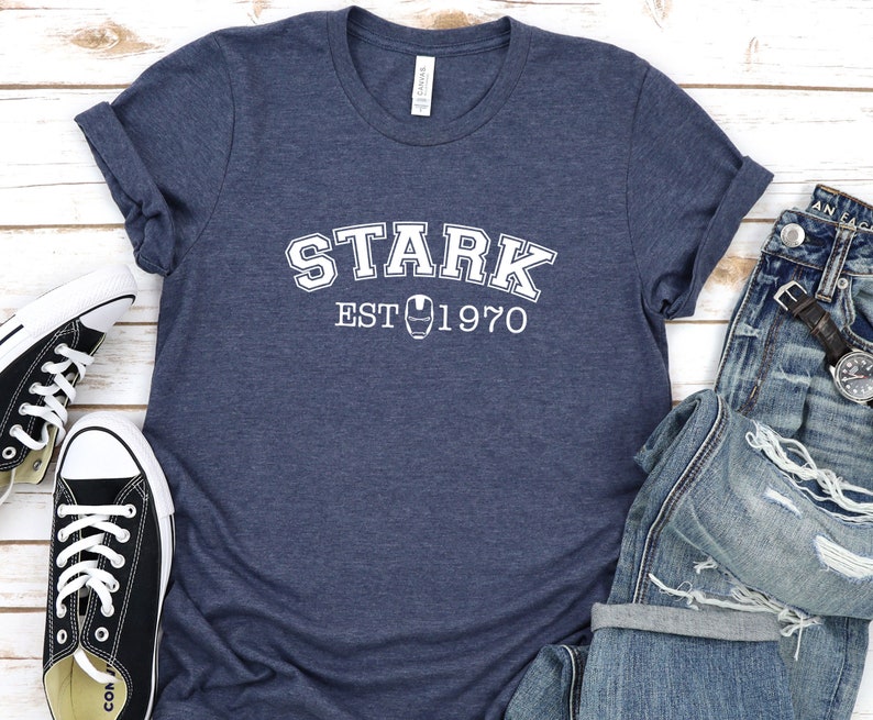 May include: A navy blue t-shirt with white text that reads "STARK EST 1970" and a small iron man symbol.