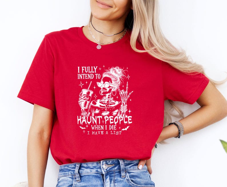 May include: Red t-shirt with a white graphic of a skeleton wearing sunglasses, holding a drink, and giving a rock-on hand gesture. The text reads "I FULLY INTEND TO HAUNT PEOPLE WHEN I DIE I HAVE A LIST."