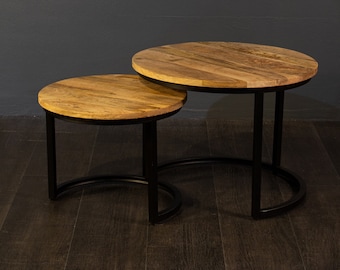 May include: A set of two round wooden nesting tables with black metal frames. The tables have a natural wood finish and are perfect for a living room or bedroom.