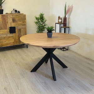 Peut inclure: Une table à manger ronde en bois avec un piétement en métal noir. La table a une finition en bois naturel et un design simple et moderne.