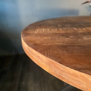 May include: Close-up of the edge of a round wooden table top. The wood is a rich brown color and has a natural, rustic finish.
