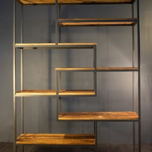 May include: A black metal bookshelf with multiple shelves made of reclaimed wood. The shelves are arranged in a geometric pattern.