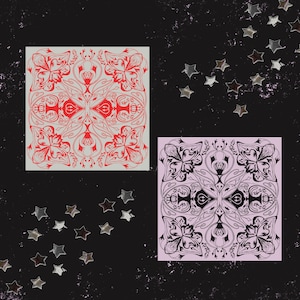 May include: Two square art prints with floral and abstract designs. One print features a red design on a light gray background. The other print has a black design on a pink background. Silver star-shaped confetti is scattered around the prints.