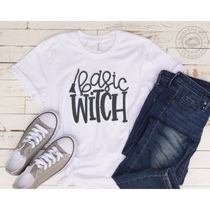May include: White t-shirt with the text "basic witch" in black lettering and a small broom graphic above the text.