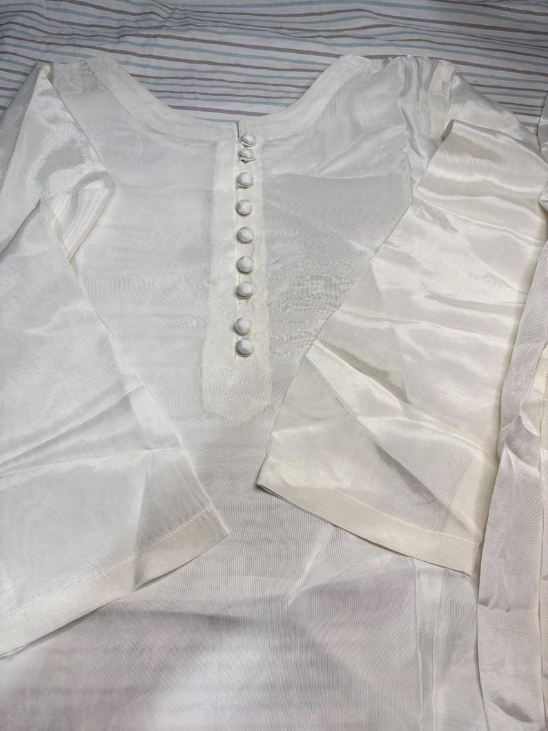 May include: A white long-sleeved shirt with a button-up closure. The shirt is made of a sheer fabric and has a loose fit.