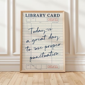 May include: A framed print featuring a vintage library card design on off-white paper with blue horizontal lines and vertical columns. The text reads: LIBRARY CARD, 031211, and Today is a great day to use proper punctuation. The frame is light wood.