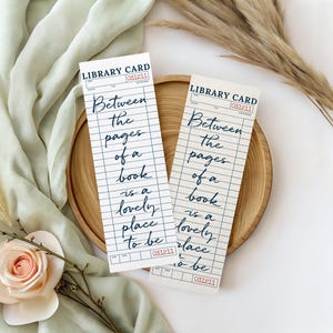 May include: Two vintage-style bookmarks with the text "Between the pages of a book is a lovely place to be." The bookmarks are designed to look like library cards, with a grid pattern and a date stamp.