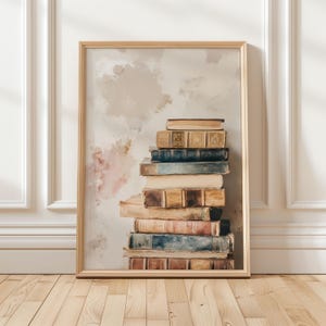 May include: A framed print featuring a stack of vintage books. The books have aged, textured covers in shades of brown, blue, and beige. The background has a soft, watercolor-like effect with muted pink and beige tones, creating a classic, literary aesthetic.