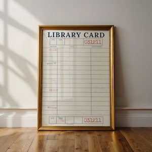 May include: Framed vintage library card with a gold-colored frame. The card has blue and red text, including the words "LIBRARY CARD" and the number "031211". The card has lines for writing and dates, with some dates visible, such as "JUN 8 '96".