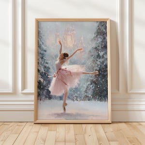 Puede incluir: Una impresión enmarcada de una bailarina con tutú rosa bailando en un bosque nevado. La obra de arte presenta un castillo iluminado en el fondo y árboles cubiertos de nieve. La bailarina está de puntillas, con los brazos elegantemente extendidos.