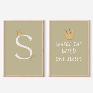 Puede incluir: Dos impresiones artísticas enmarcadas con un fondo verde claro. Una presenta una corona dorada sobre una letra "S" blanca con el nombre "Sage" en cursiva. La otra impresión tiene una corona dorada sobre el texto "Where the Wild One Sleeps."