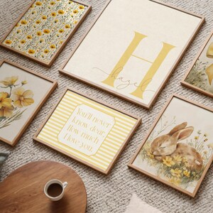 Soft yellow nursery gallery wall featuring bunny rabbit decor, daisy floral patterns, custom initial print, and whimsical cottagecore artwork.