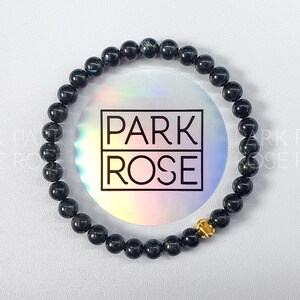 May include: A black beaded bracelet with a gold accent. The bracelet is on a white background with a holographic sticker that says "PARK ROSE".