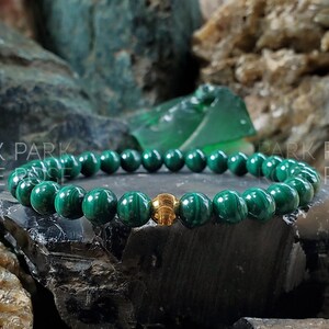 May include: A green malachite gemstone bracelet with a gold bead accent.