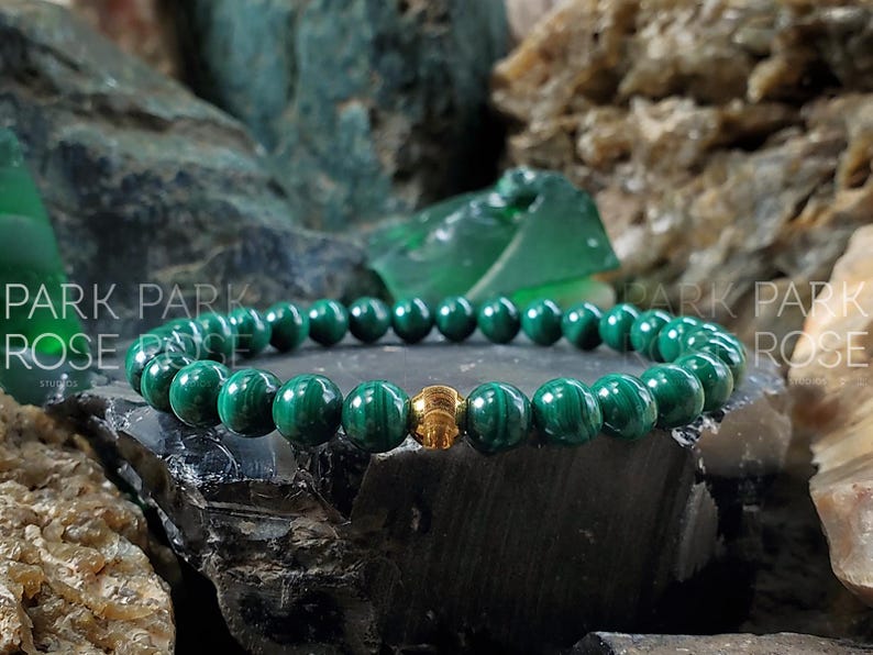 May include: A green malachite gemstone bracelet with a gold bead accent.