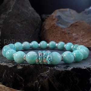 May include: A turquoise blue gemstone bracelet with a silver and turquoise patterned bead in the center.