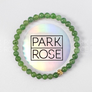 May include: A green jade stone bracelet with a gold clasp. The bracelet is made of round beads and has a simple design.