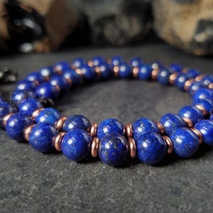 May include: A double-strand necklace made of dark blue lapis lazuli beads separated by copper spacers.
