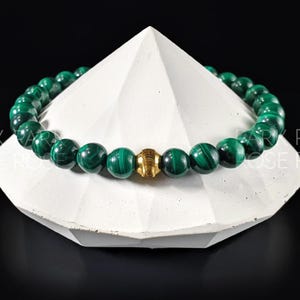 May include: A green malachite beaded bracelet with a gold accent bead.