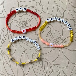 May include: Three beaded bracelets with different colored beads and letter beads spelling out "RED", "FEARLESS", and "STARLIGHT".