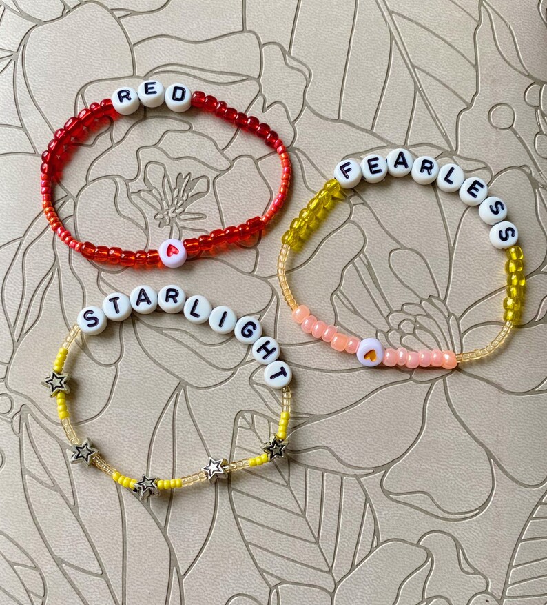 May include: Three beaded bracelets with different colored beads and letter beads spelling out "RED", "FEARLESS", and "STARLIGHT".