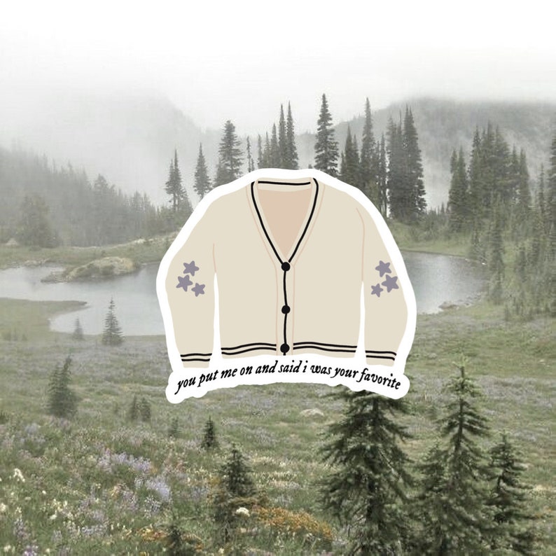 May include: A white cardigan with black trim and purple star accents. The cardigan has a button closure and the text "you put me on and said i was your favourite" is printed on the bottom.