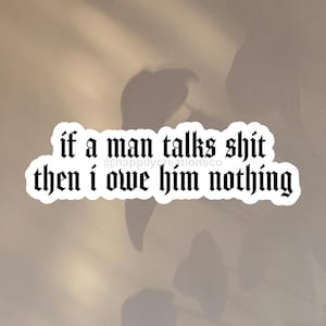 Può includere: Un adesivo bianco con testo nero in carattere gotico che recita "if a man talks shit then i owe him nothing". L'adesivo ha un bordo decorativo. Lo sfondo è beige neutro con ombre.