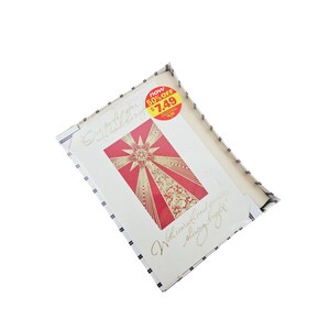 Könnte beinhalten: Eine weiße Karte mit einem roten und goldenen Sternmuster. Die Karte trägt den Text "One perfect star to shine this Christmas" und "With love and best wishes for a shining Christmas night". Ein roter und gelber Aufkleber auf der Karte lautet "Now 50% off €7.49 €15.00".